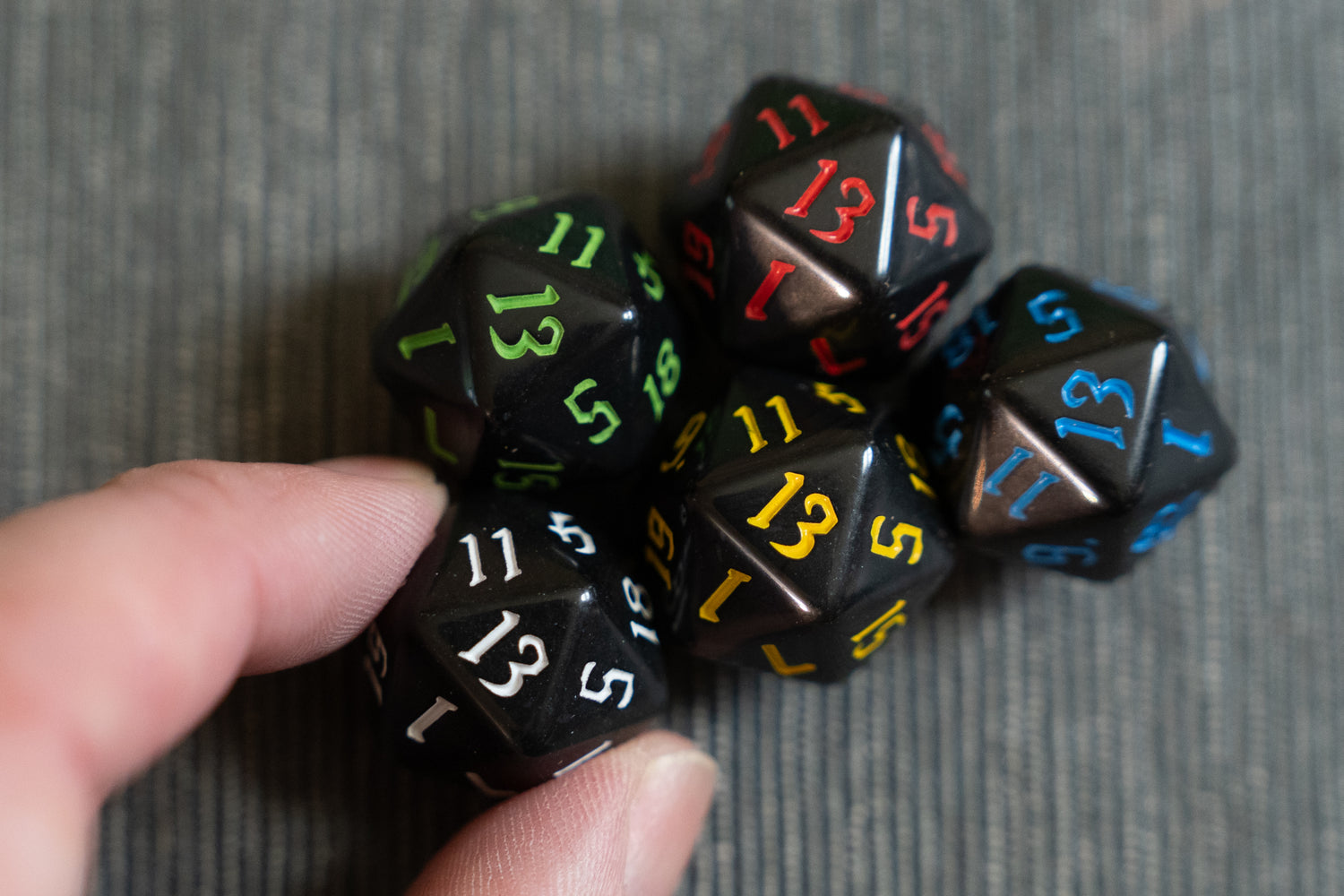 fingers holding dungeons and dragons (aka dnd or d&d) game dice d20