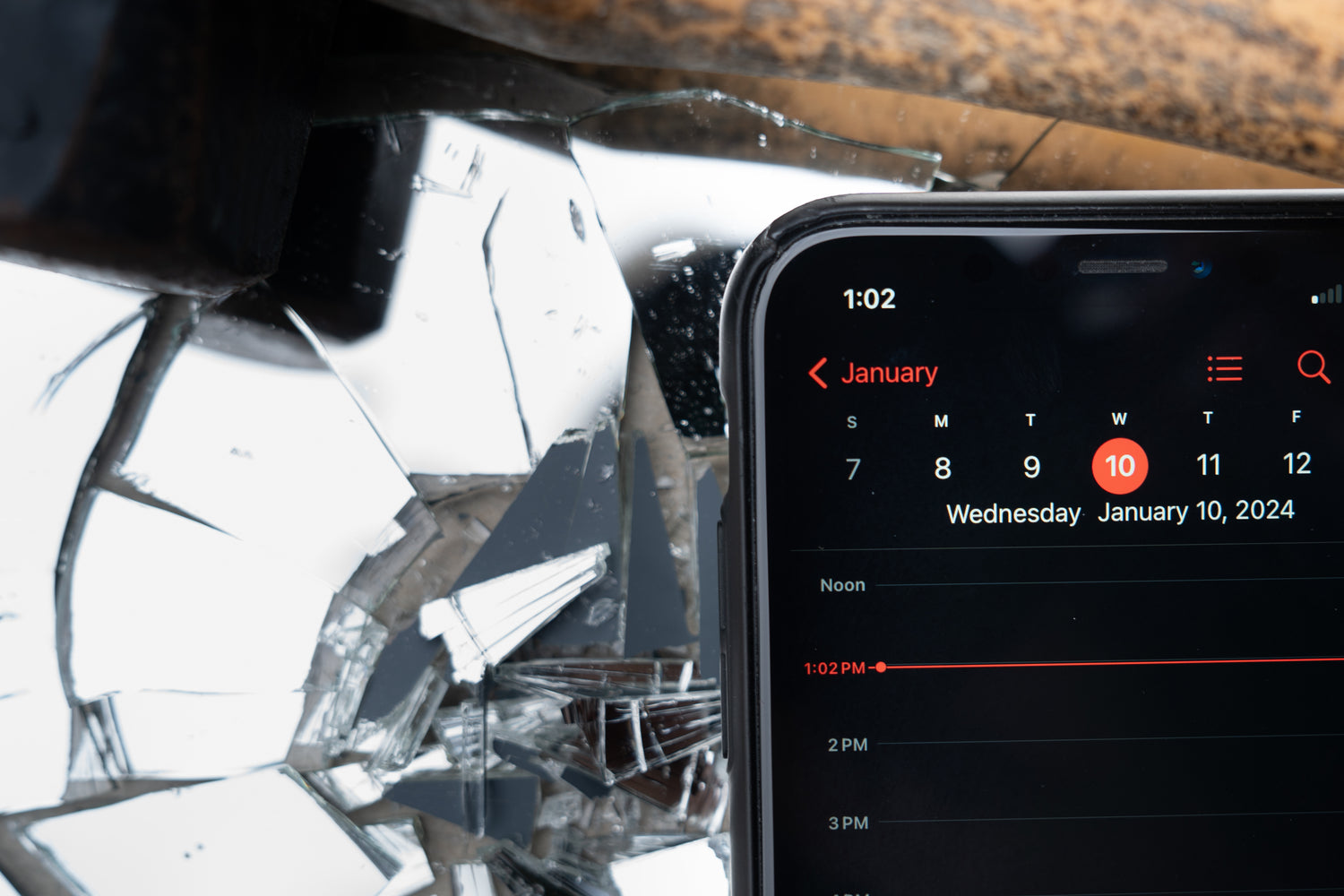 Smartphone displaying a calendar app with a date with a broken mirror in the background