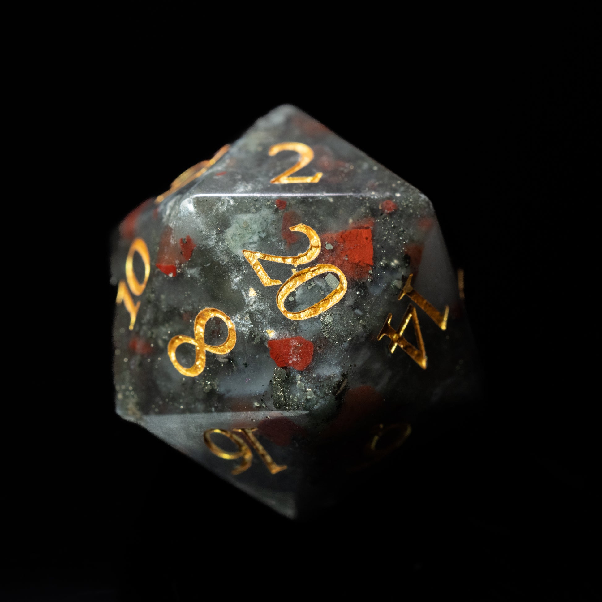 bloodstone glass gemstone dungeons and dragons (aka dnd or d&d) d20 game die or dice with gold numbers on a black background